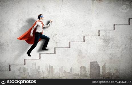 Walking superhero. Young confident superman in mask and cape walking on ladder