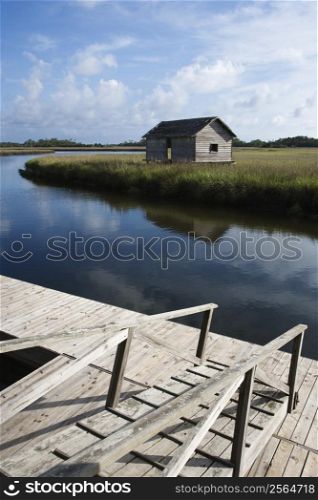 Walkway down to dock on creek with weathered building.
