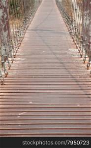 Walkway on the bridge. The metal rod attached to a rope bridge across the river.