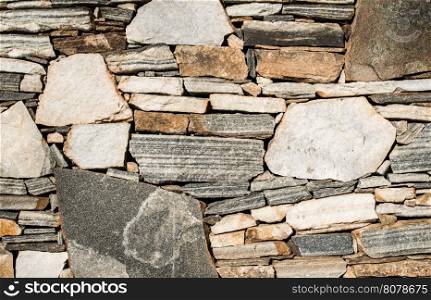 Wall built of stones. Densely arranged stones. Sun light