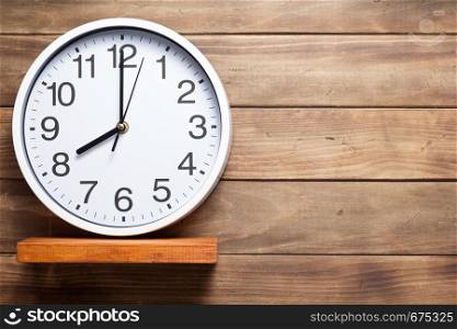 wall clock at shelf on wooden background texture