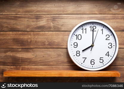 wall clock at shelf on wooden background texture