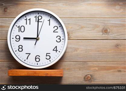 wall clock at wooden shelf on wall background texture