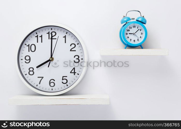 wall clock at wooden shelf on white background