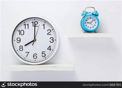 wall clock at wooden shelf on white background