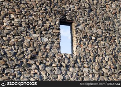 Wall of an old abandoned castle overlooking the blue sky through the window