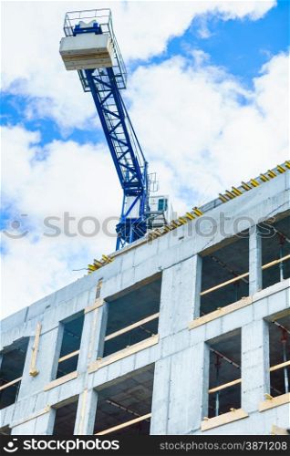 Wall of concrete building and crane on sky background. Construction works. Industrial scene.. Building construction and crane on sky background