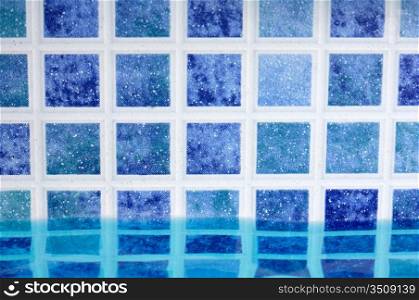 Wall of swimming pool with water of blue color