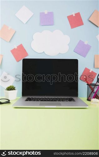 wall with cloud paper adhesive notes laptop with blank black screen