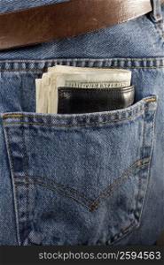 Wallet filled with paper currency in the pocket of a pair of jeans