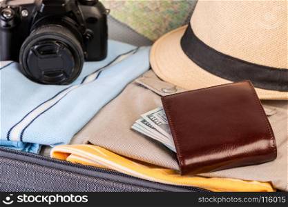 wallet with money, camera and clothing close-up in suitcase
