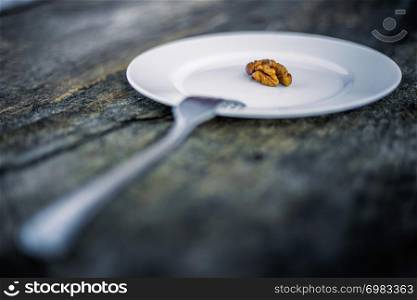 Walnut in a plate and fork on a wooden background. Shallow depth of field.