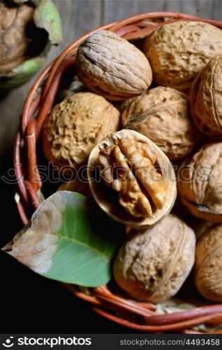 Walnut in basket and whole walnuts on rustic old wood