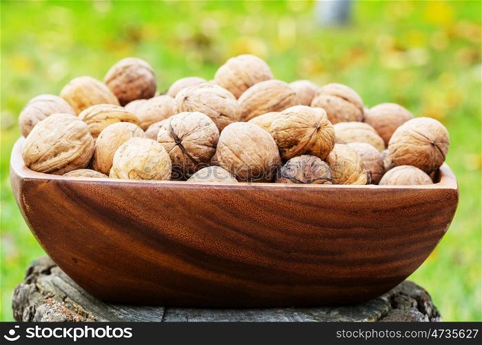 Walnut kernels in a wooden bowl on green background