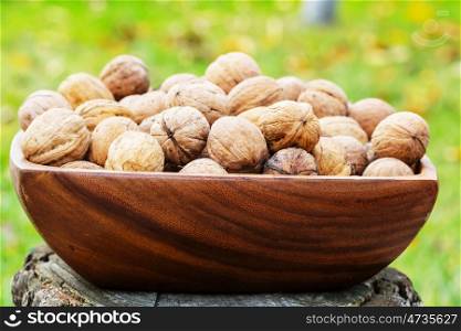 Walnut kernels in a wooden bowl on green background