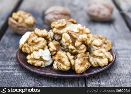 Walnut kernels lie in a bowl on a rustic old wooden table. Fresh walnuts. Harvest walnuts.. Walnut kernels lie in a bowl on a rustic old wooden table. Fresh walnuts.