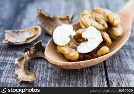 Walnuts and walnut kernels lie in a spoon on a rustic old wooden table. Kernels of walnuts. Harvest walnuts.. Walnuts and walnut kernels lie in a spoon on a rustic old wooden table. Kernels of walnuts.