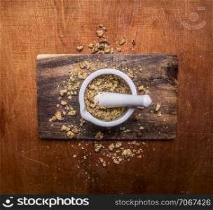 walnuts, crushed in a mortar on cutting board on wooden rustic background top view close up