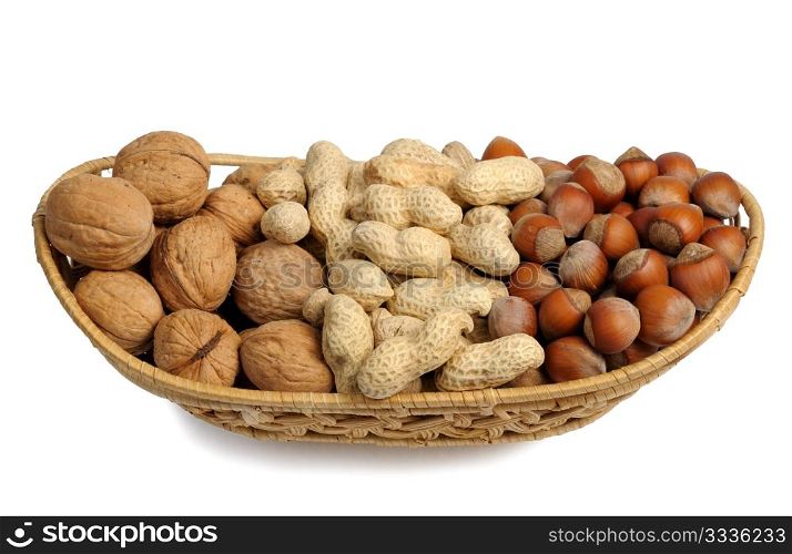 Walnuts, hazelnuts and peanuts in a wicker basket on a white background, isolated