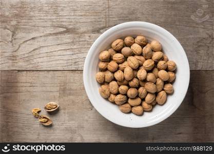 Walnuts in a bowl on a wooden background. Top view