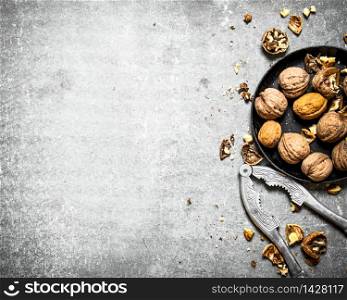 Walnuts in bowl with Nutcracker. On the stone table.. Walnuts in bowl with Nutcracker.