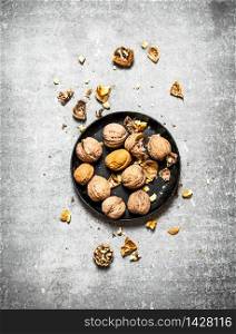 Walnuts in the old plate. On the stone table.. Walnuts in the old plate.