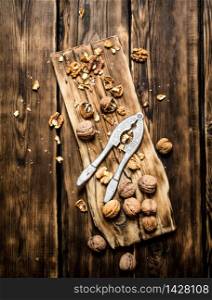 Walnuts with Nutcracker on the Board. On a wooden table.. Walnuts with Nutcracker on the Board.