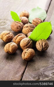 Walnuts with shell and green leaf on the wooden table