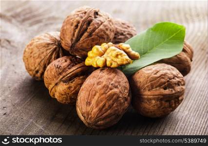 Walnuts with shell and green leaf on the wooden table