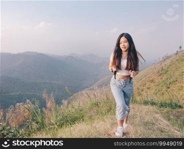 wanderlust and travel concept from Happy asian young woman walking trail in mountain with amazing view. Trekking mountain on National park in Thailand.