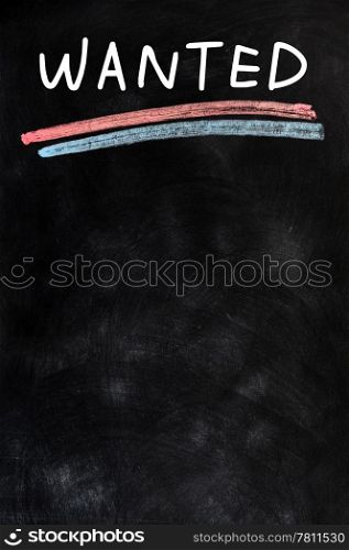 ""Wanted" handwritten with white chalk on a blackboard"