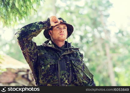 war, army and people concept - young soldier or ranger wearing military uniform in forest