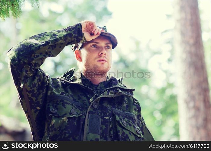 war, army and people concept - young soldier or ranger wearing military uniform in forest