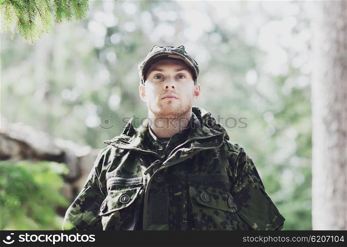 war, army and people concept - young soldier or ranger wearing military uniform in forest