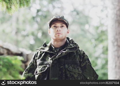 war, army and people concept - young soldier or ranger wearing military uniform in forest