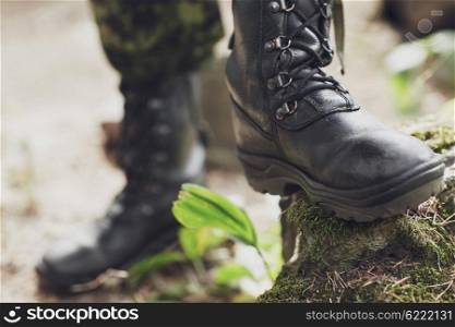 war, hiking, army and people concept - close up of soldier feet in army boots in forest