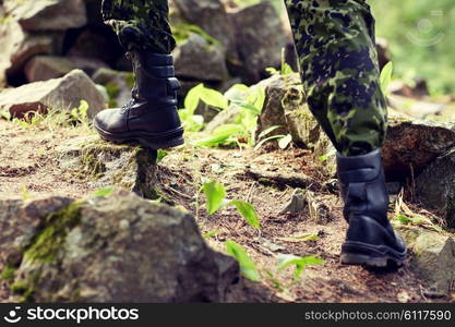 war, hiking, army and people concept - close up of soldier legs climbing on rocks in forest