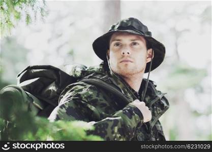 war, hiking, army and people concept - young soldier or ranger with backpack in forest