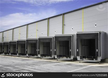 Warehouse loading docks on a sunny day. Open gates of an industrial warehouse. Storehouse doors in a row. Distribution warehouse with open doors.