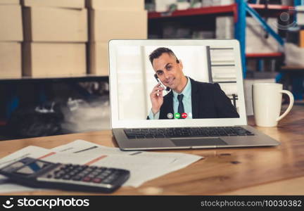 Warehouse staff talking on video call at computer screen in storage warehouse . Online software technology connects people working in logistic factory by virtual conference call on internet network .