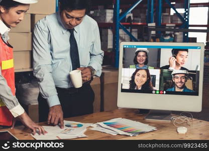 Warehouse staff talking on video call at computer screen in storage warehouse . Online software technology connects people working in logistic factory by virtual conference call on internet network .. Warehouse staff talking on video call at computer screen in storage warehouse