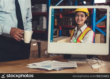 Warehouse staff talking on video call at computer screen in storage warehouse . Online software technology connects people working in logistic factory by virtual conference call on internet network .. Warehouse staff talking on video call at computer screen in storage warehouse