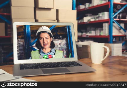 Warehouse staff talking on video call at computer screen in storage warehouse . Online software technology connects people working in logistic factory by virtual conference call on internet network .