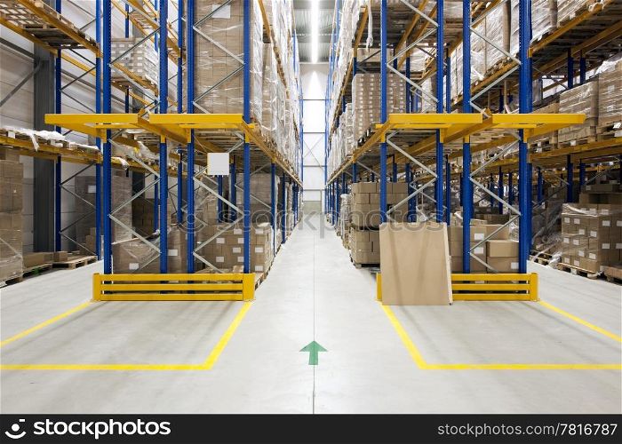 Warehouse with racks and shelves, filled with cardboard boxes, wrapped in foil on wooden pallets