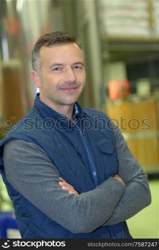 warehouse worker smiling at camera with arms crossed