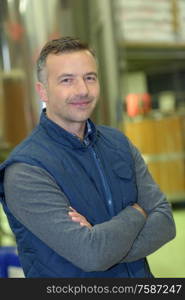 warehouse worker smiling at camera with arms crossed