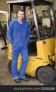 Warehouse worker standing by forklift