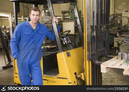 Warehouse worker standing by forklift