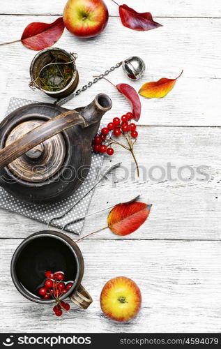 Warm apple berry tea. clay kettle with tea with berries on autumn background