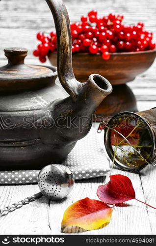 Warm apple berry tea. clay kettle with tea with berries on autumn background